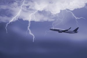Passenger airplane travelling through sky against stormy bolt cloudscape